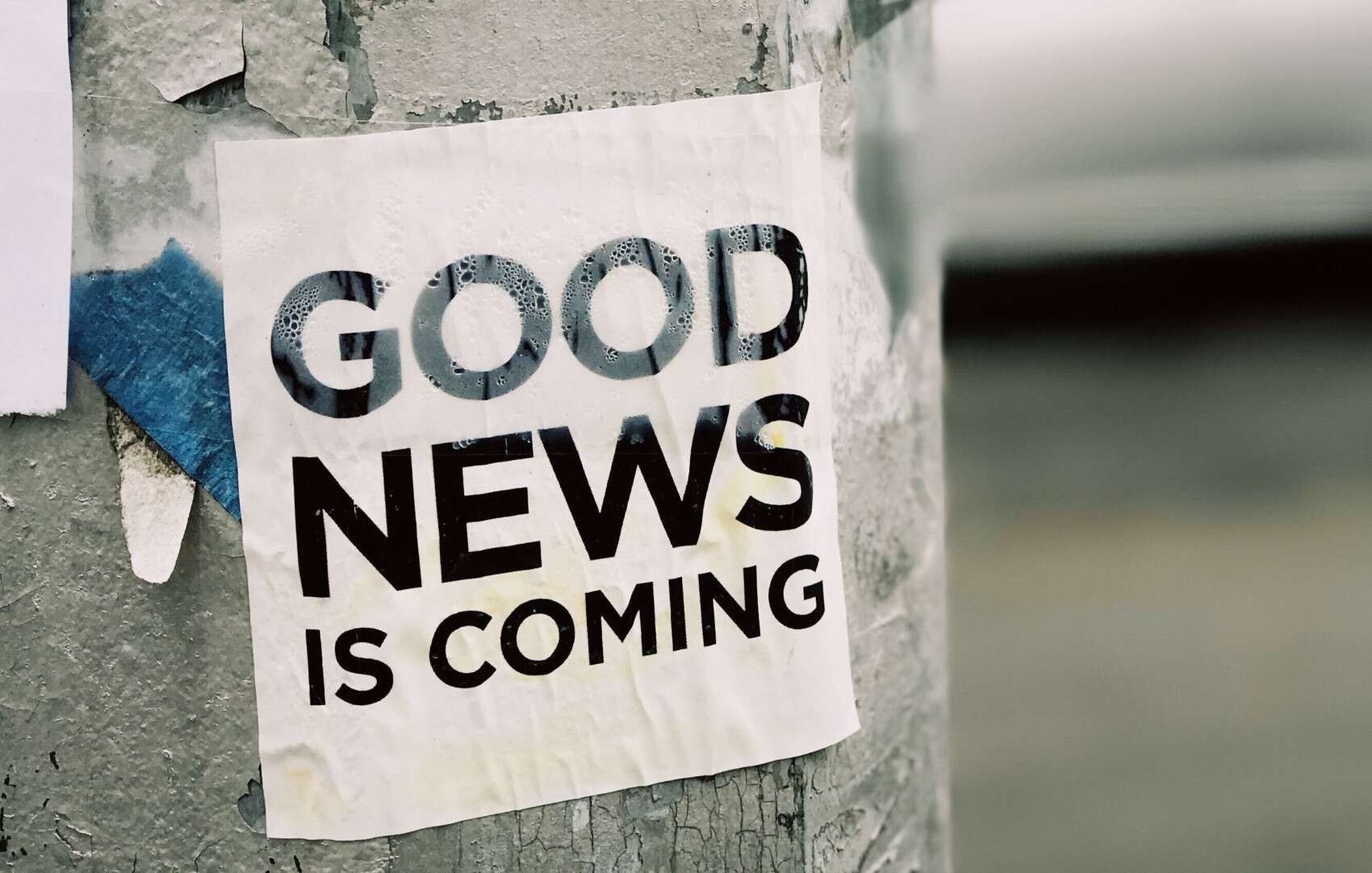 Illustrasjonsbilde med en stolpe med en plakat der det står "Good news is coming"